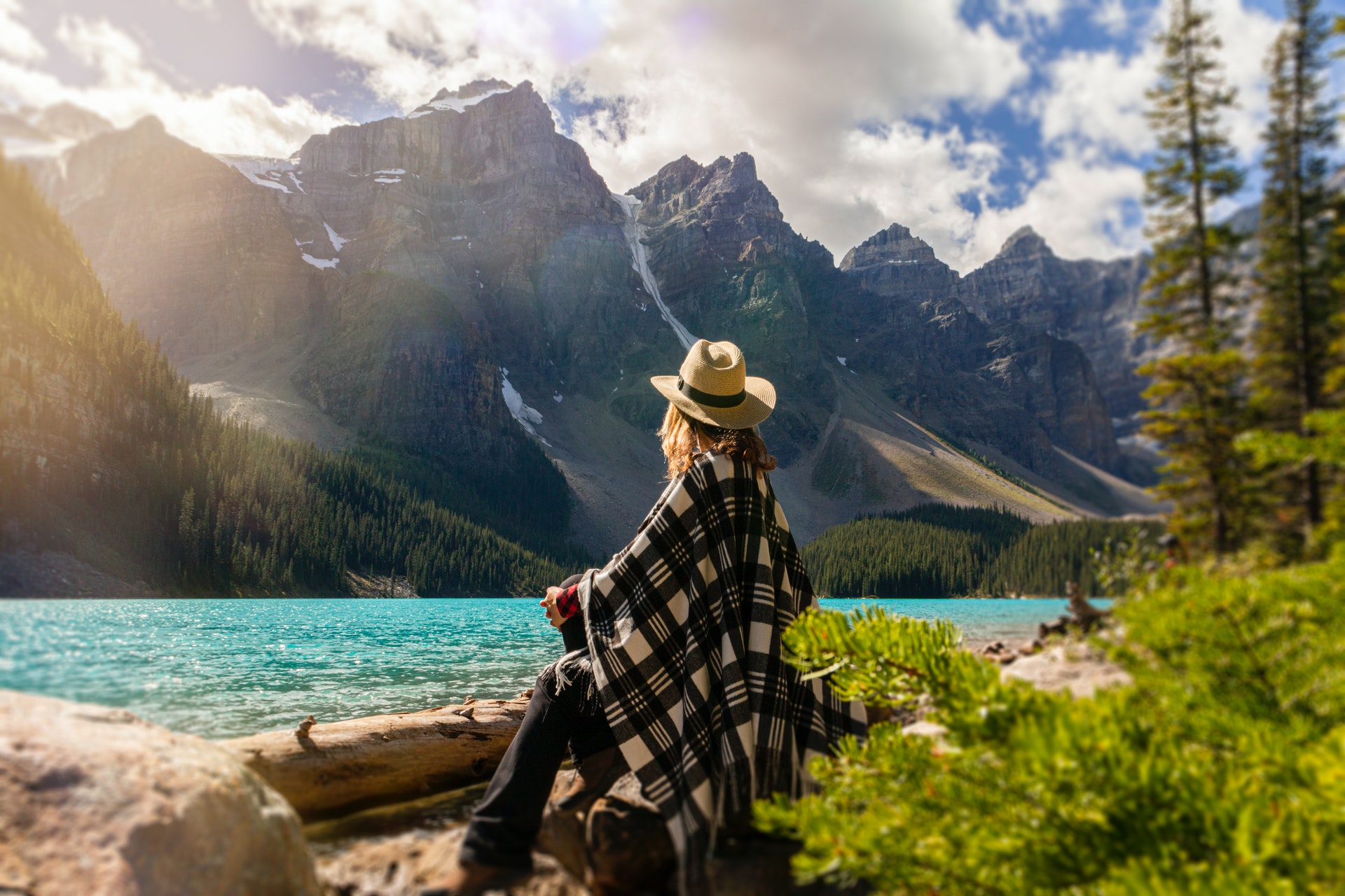 woman sitting by lake looking at mountains