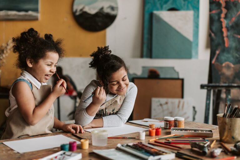 Two little girls laugh as they do an art project.