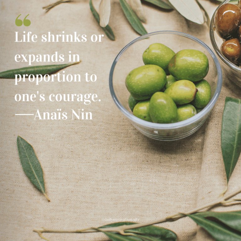 Bowl of green olives on a burlap surface surrounded by olive branches and leaves.