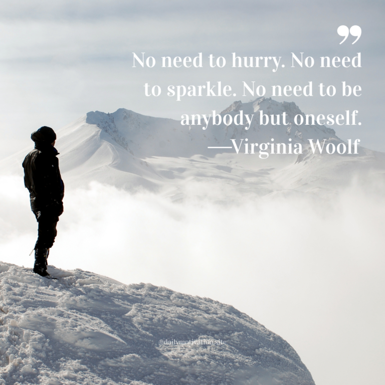 Person standing on a snowy mountain ridge overlooking fog and distant peaks under a pale sky.
